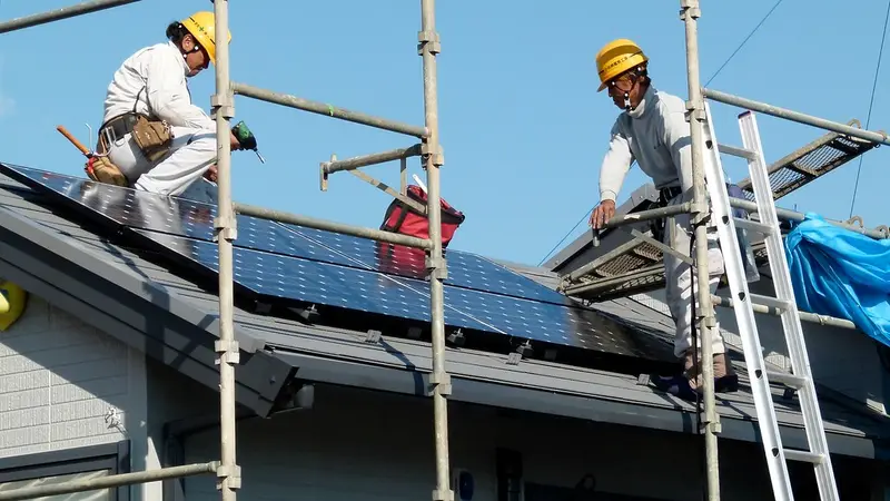 Twee installateurs met helm aan het werk op een dak tijdens een installatie