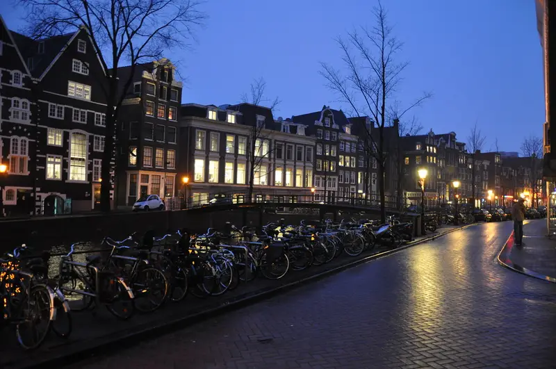 Nederlandse grachtenpanden en rijtjeshuizen langs een straat in de schemering